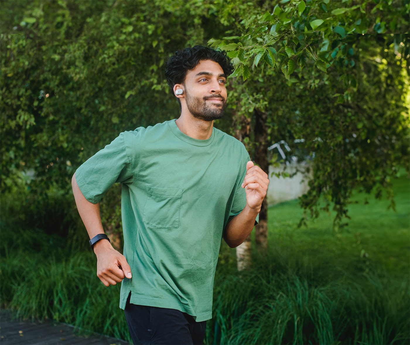 Man in green t-shirt running past trees in a park as part of an exercise routine and health management for type 1 diabetes.